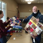 Volunteer Rowan accepting handmade quilts from Joe